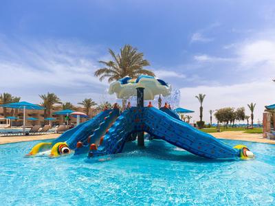 Area giochi acquatica colorata con scivoli e ombrelloni in piscina di un hotel sotto un cielo blu.