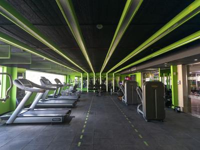 Moderner Fitnessraum mit Laufbändern und Kraftgeräten in einem hellgrünen Raum.