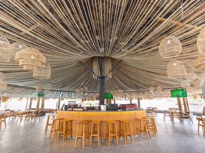 Modernes, offenes Barinterieur mit rundem Tresen und ungewöhnlicher Deckengestaltung aus Stäben.