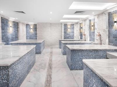 Moderner Spa-Raum mit Marmorliegen und blauen Fliesen an den Wänden.