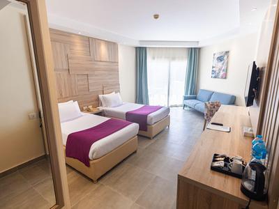 Hell eingerichtetes Hotelzimmer mit zwei Einzelbetten, Schreibtisch und Balkon