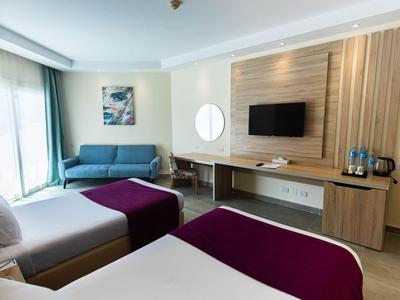 Modern eingerichtetes Hotelzimmer mit Sofa, Schreibtisch und Wand-TV.