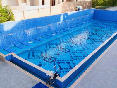 Leerer rechteckiger Pool mit Teilabdeckung neben weißem Gebäude bei Sonnenschein