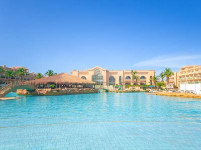 Großer Hotelpool mit klar blauem Wasser und Sonnenterrasse unter klarem Himmel.