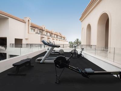 Moderner Fitnessbereich auf einer offenen Dachterrasse mit Laufband und Rudergerät.