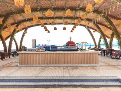 Offener Pavillon mit geflochtenem Dach und Bar in tropischem Hotelresort