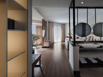 Modernes Hotelzimmer mit Holzboden, gemütlichem Sitzbereich und dekorativen Spiegeln.