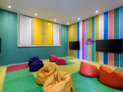Bunt gestalteter Kinderspielraum mit gemütlichen Sitzsäcken und Fernsehern an den Wänden.