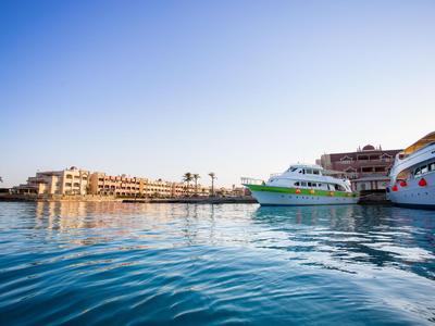 Boote im Hafen mit Hotelgebäuden im Hintergrund bei klarem Himmel.