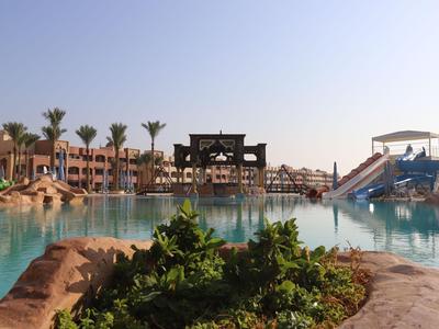 Großer Hotelpool mit Wasserrutschen und Palmen unter klarem Himmel