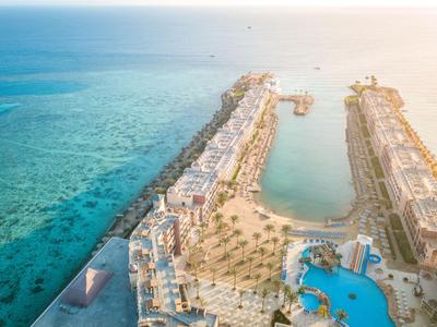 Luftaufnahme einer Lagune mit Hotels, Pools und Palmen an einem tropischen Küstenresort.