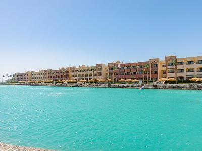 Grand complexe hôtelier à plusieurs étages en bord de mer avec eau turquoise sous un ciel clair.