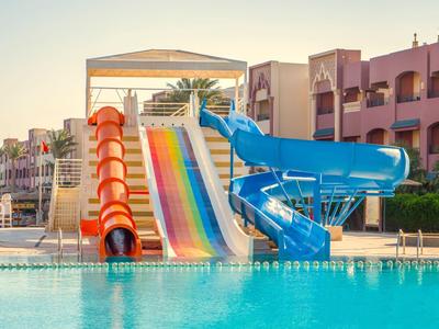 Toboggans aquatiques multicolores et un toboggan en spirale bleu à côté d'une piscine dans un complexe hôtelier.