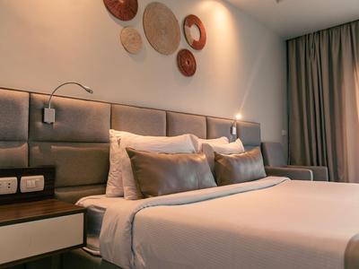 Chambre d'hôtel moderne avec grand lit double, tables de nuit et plaques murales décoratives.