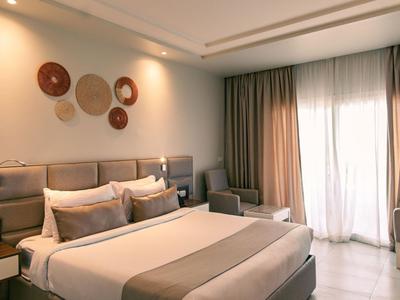 Chambre d'hôtel moderne avec grand lit, panneaux muraux décoratifs et lumière naturelle.
