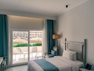 Une chambre d'hôtel lumineuse avec deux lits simples et une grande fenêtre donnant sur une terrasse.