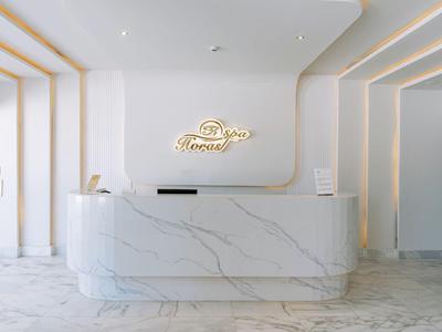 Moderner Hotel-Empfang mit weißem Marmor und dezentem LED-Logo an der Wand.