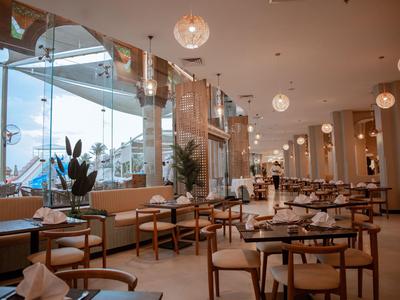 Restaurant lumineux et moderne avec de grandes fenêtres, des chaises confortables et des tables dans un hôtel de voyage.