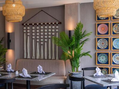 Restaurant moderne avec des œuvres murales décoratives, des plantes et des tables dressées.