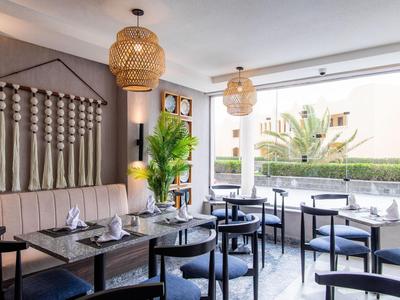 Restaurant moderne avec tables en bois, chaises bleues et grandes fenêtres.