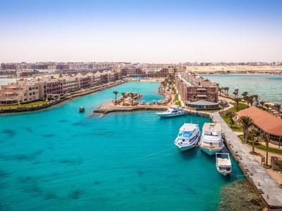 Blick auf eine Lagune mit Booten, Palmen und Gebäuden an einem sonnigen Strandresort.