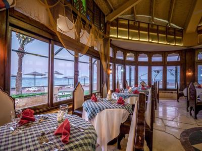 Gemütliches Restaurant mit Holzmöbeln und Blick auf den Strand und das Meer.