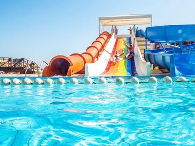Bunte Wasserrutschen über einem Schwimmbecken unter klarem Himmel