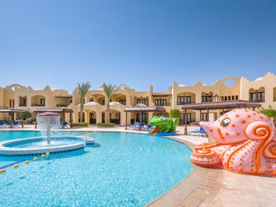 Ein Hotel mit großem blauen Pool, Springbrunnen und oranger Oktopus-Skulptur unter klarem Himmel.