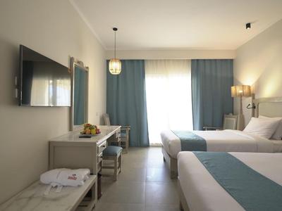 Double room with two beds, flat-screen TV, and desk, bright and modern design.