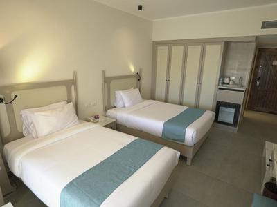 Modern hotel room with two single beds and a desk against the wall.