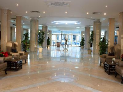 Großer, heller Hotellobby mit Marmorfußboden, Säulen und komfortablen Sitzbereichen.