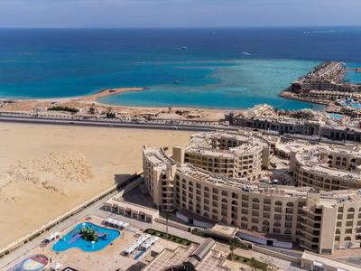 Großes Hotel an der Küste mit Pool und Blick auf das blaue Meer und die Sandlandschaft.