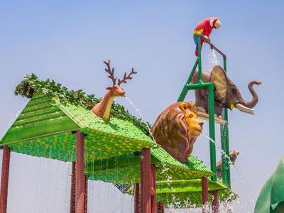 Green play area with animal figures like deer, lion, elephant, and turtle outdoors.