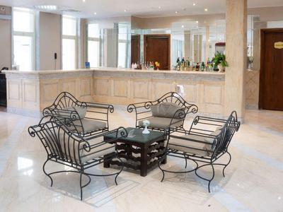 Helle Hotellobby mit cremefarbenem Empfangstresen und schwarzem Eisenmöbel-Set.