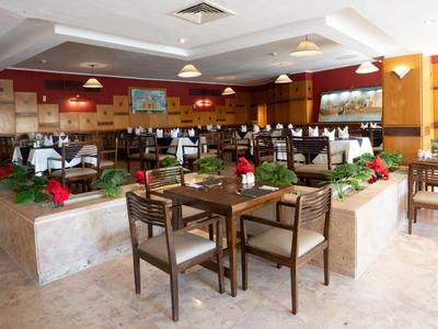 Modern restaurant area with wooden furniture, plants, and light flooring.