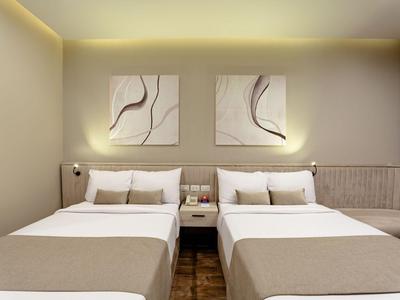 Hotelzimmer mit zwei Doppelbetten, abstrakter Wandkunst und modernem Design.