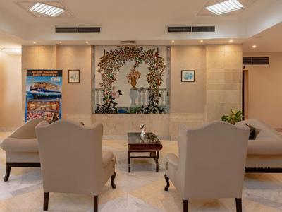 Hotel-Lounge mit zwei Stühlen, zwei Sofas und einem Tisch vor einer dekorativen Wand