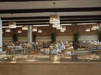 Ein modernes Restaurant mit holzvertäfelten Wänden, eleganten Kronleuchtern und gedeckten Tischen.