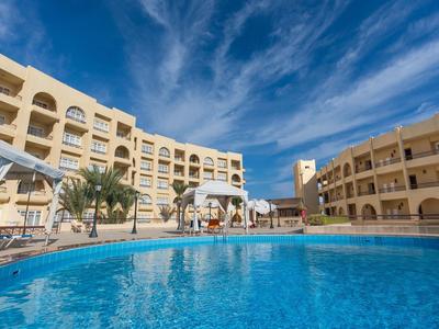 Hotelanlage mit großzügigem Pool, Sonnenschirmen und blauer Himmel.