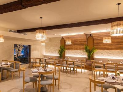 Eleganter Speiseraum mit Holzmöbeln, warmem Licht und Pflanzen in einem Hotel.