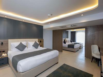 Moderní hotelový pokoj s manželskou postelí, posezením a psacím stolem.