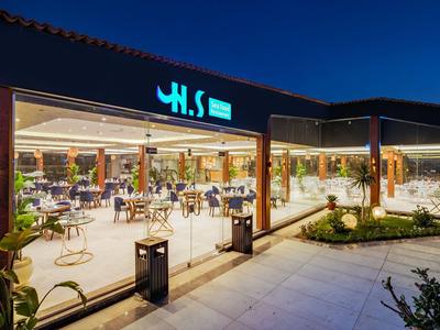 Moderní osvětlená venkovní restaurace v noci s posezením a otevřenou atmosférou.