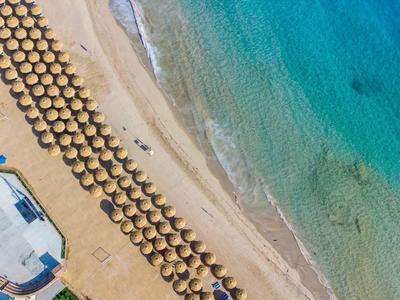 Letecký pohled na pláž s řadami slunečníků a čistou tyrkysovou vodou.