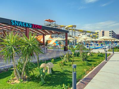 Vodní skluzavka v aquaparku s modrým bazénem a jasnou modrou oblohou.