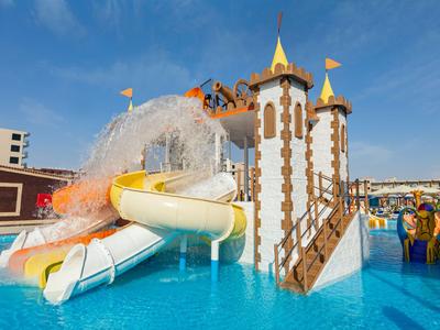 Vodní skluzavka v aquaparku s modrým bazénem a jasnou modrou oblohou.