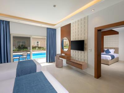 Moderní hotelový pokoj se dvěma postelemi, televizí, psacím stolem a výhledem na bazén přes posuvné dveře