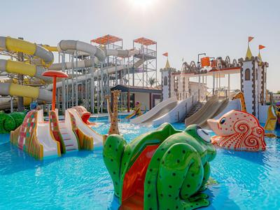 Barevný vodní park s skluzavkami, vodními atrakcemi a čistým modrým bazénem za slunečného dne.