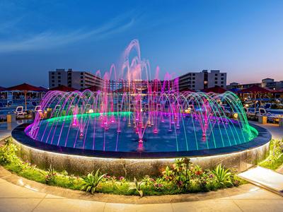 Barevná osvětlená fontána v moderním venkovním prostoru za soumraku