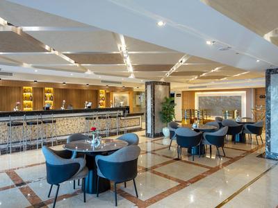 Moderní hotelový lounge prostor se stoly, židlemi a dlouhým barem.