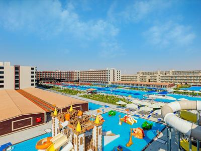 Velký hotel s vodním parkem s barevnými skluzavkami a bazény pod modrou oblohou.